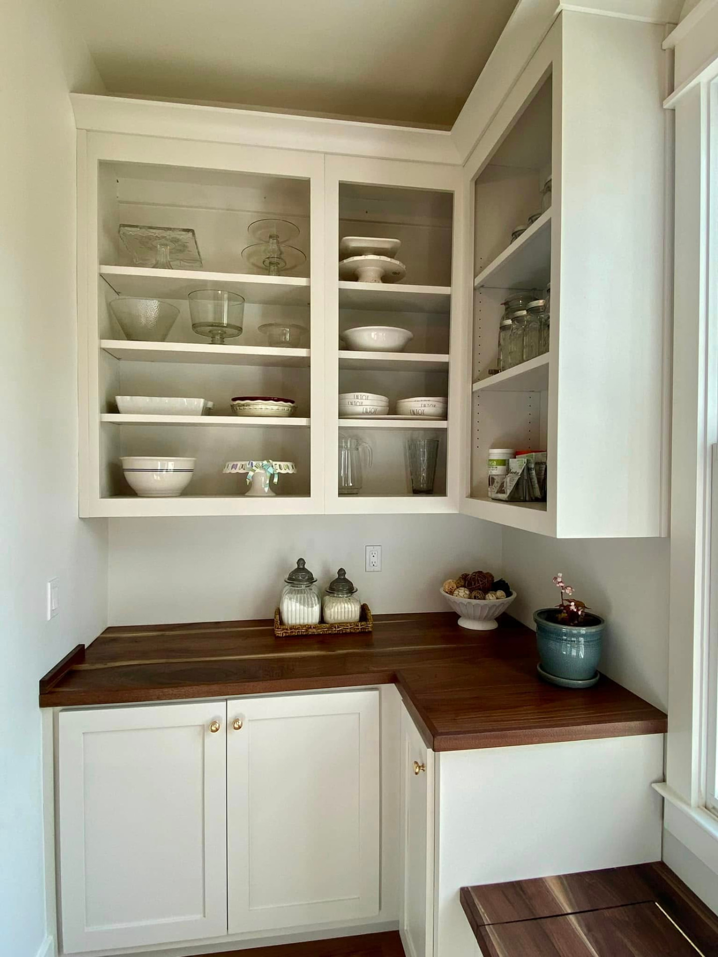Butler's pantry with white cabinetry, glass doors, and a walnut countertop